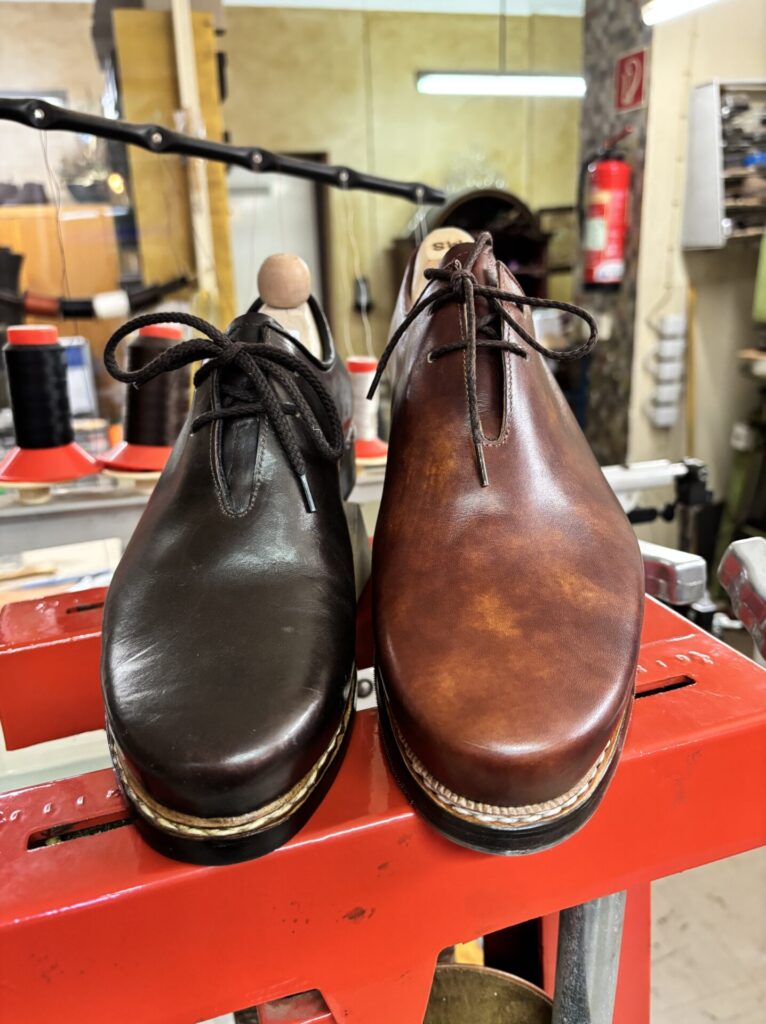 Zwei Haferlschuhe in Dunkelbraun und Cognac auf der Werkbank