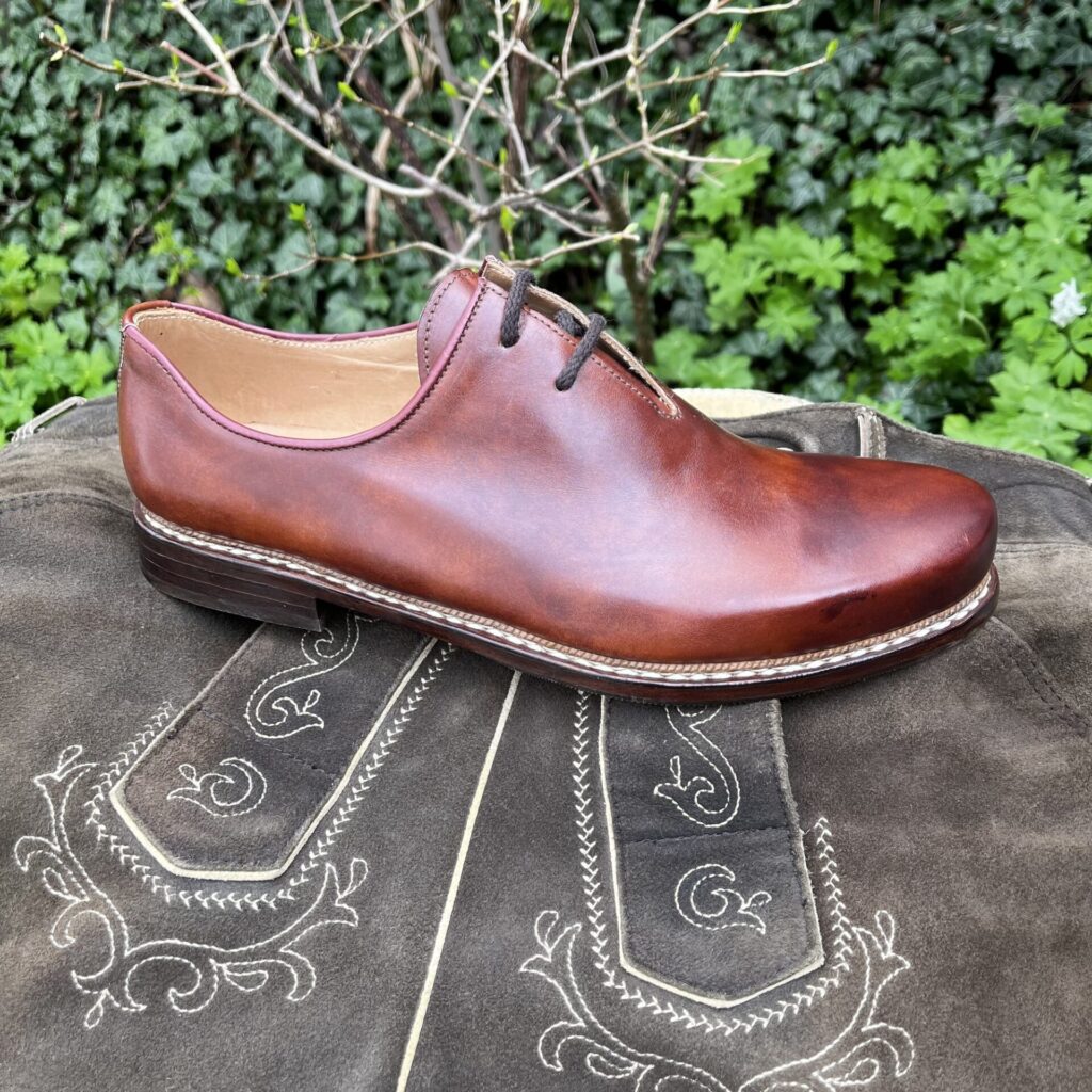 Rotbrauner Haferlschuh auf einer bestickten Lederhose