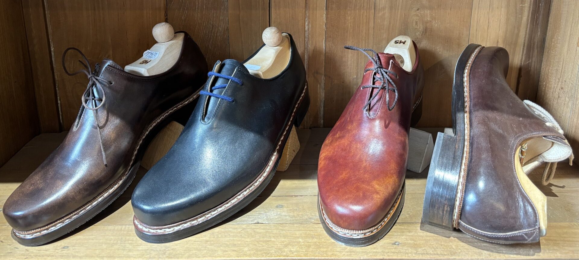 Vier handgemachte Haferlschuhe in verschiedenen Ledern im Regal der Münchener Schuhwerkstätten